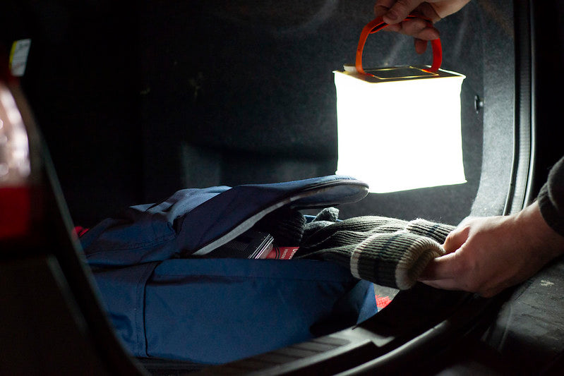 Source: Molly McFaddin. Person with LuminAID lantern takes hat from backpack.