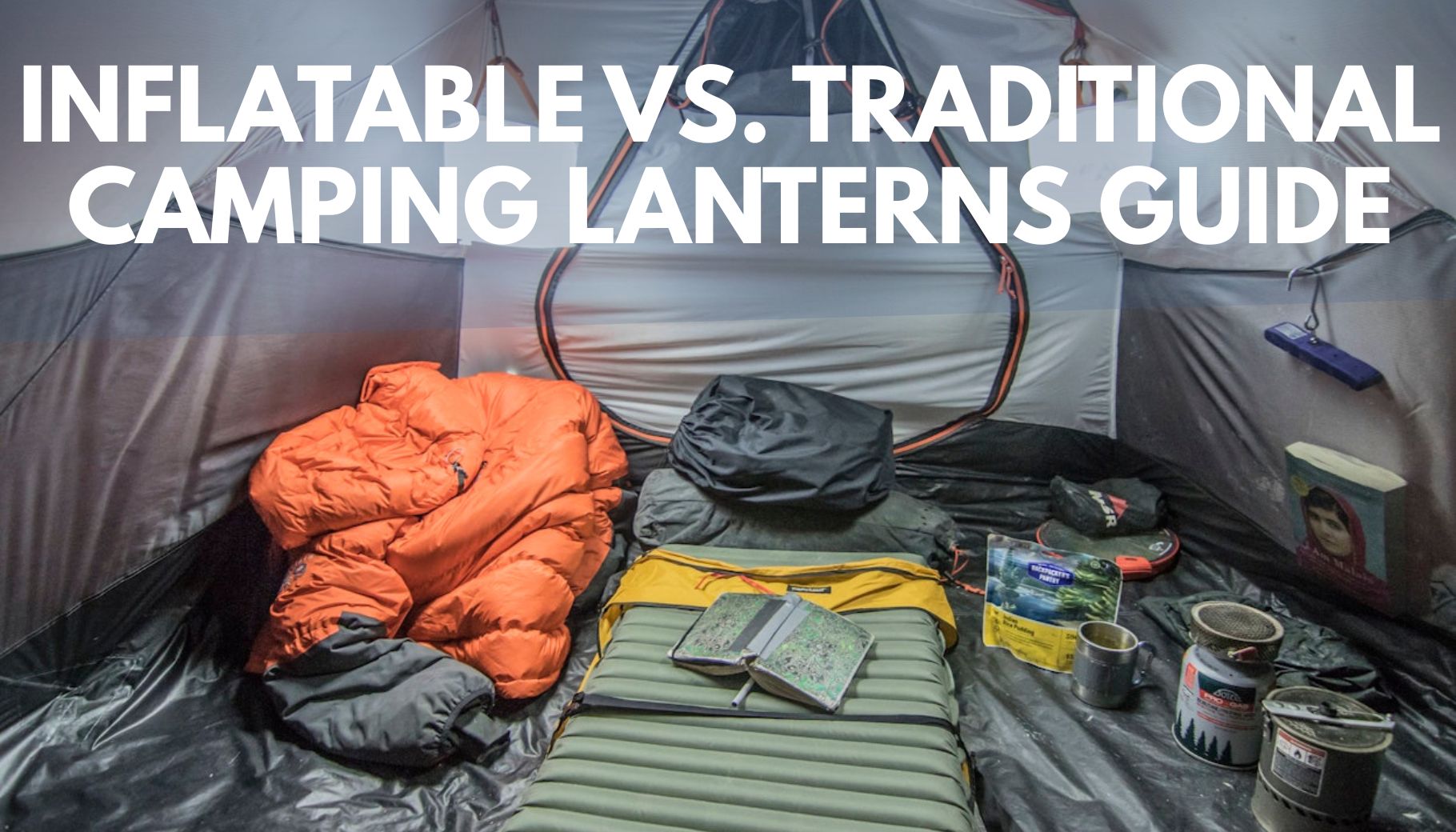 the inside of a camping tent with a sleeping pad, blanket, and various other camping gear
