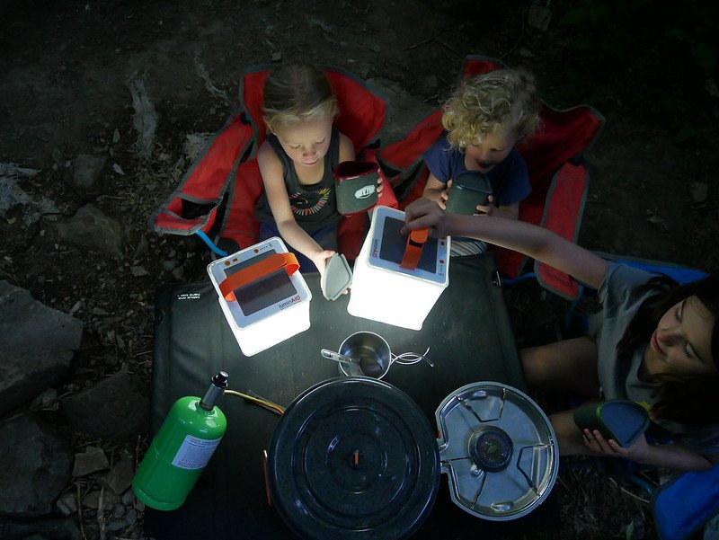 Happy camping family huddled around LuminAID lanterns. Source: Kati Whelan