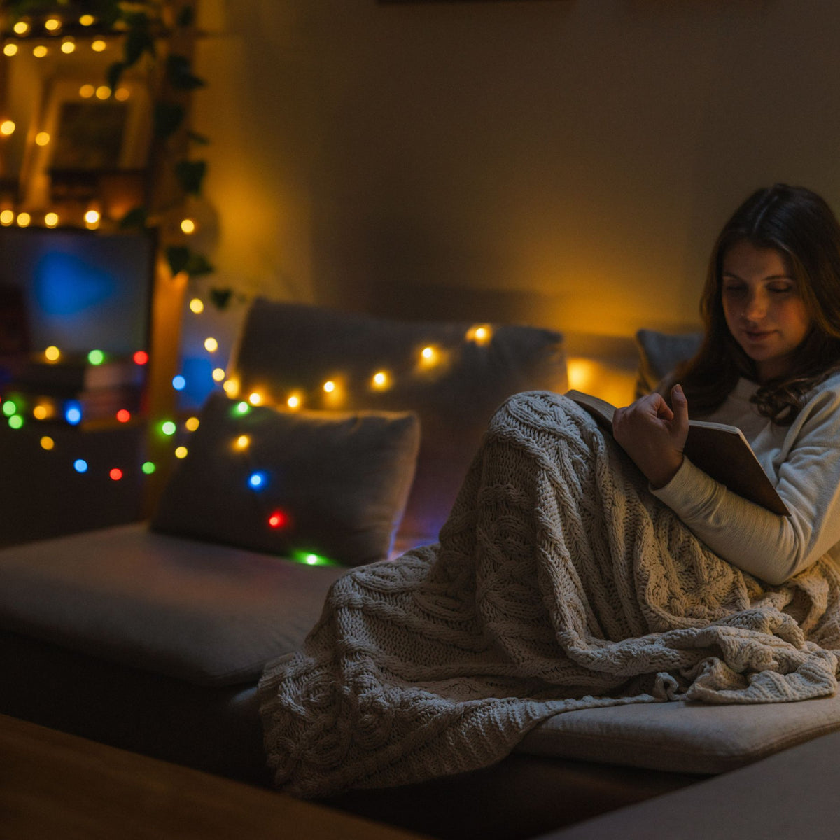 Woman reading in a living room with USB string lights