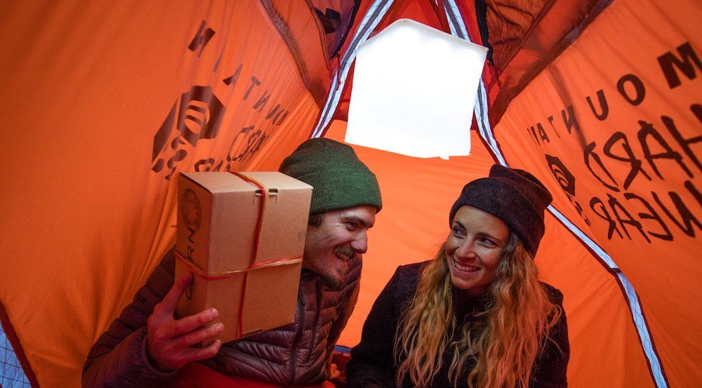 Man and a women in a tent exchanging gifts under a LuminAID