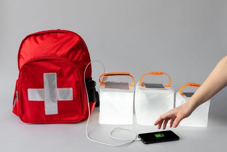 Red emergency backpack with solar lanterns and a charging cell phone