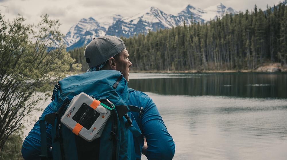 Man with lantern on his backpack hiking in wilderness.