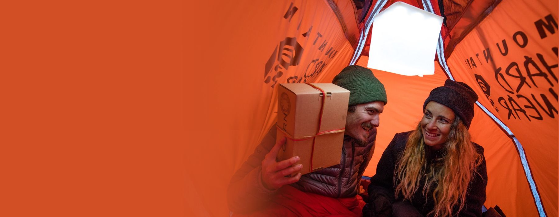 Man and a women in a tent exchanging gifts under a LuminAID