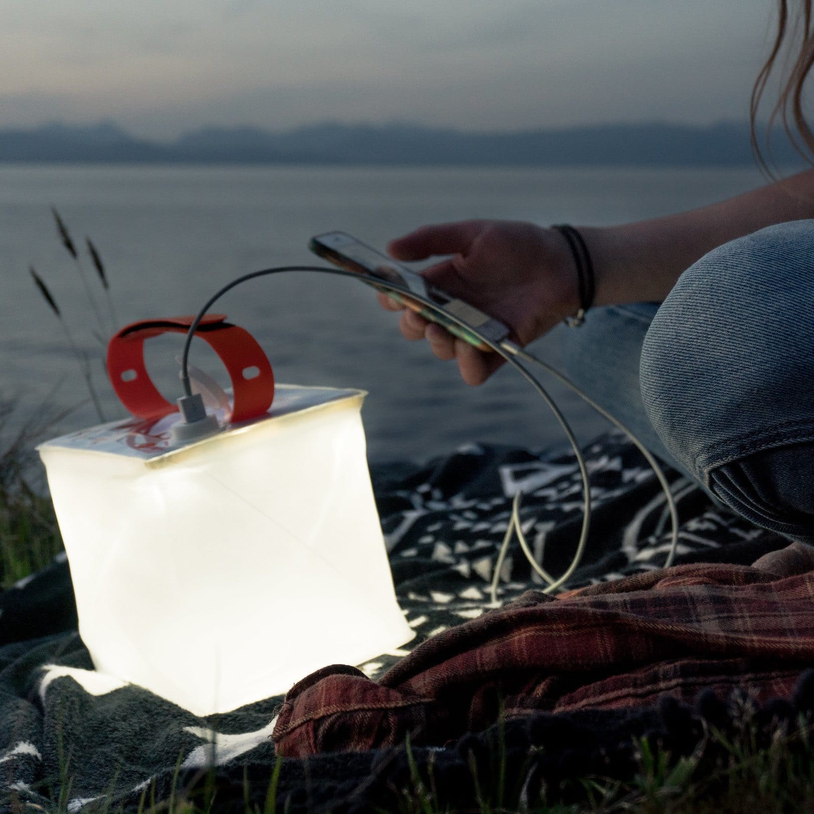 Packlite Max Power Lantern being used as a light and a phone charger.