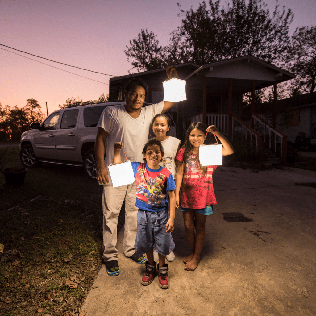 Happy family holding up 3 lanterns outside home.