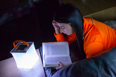 Woman reading a book using a LuminAID lantern