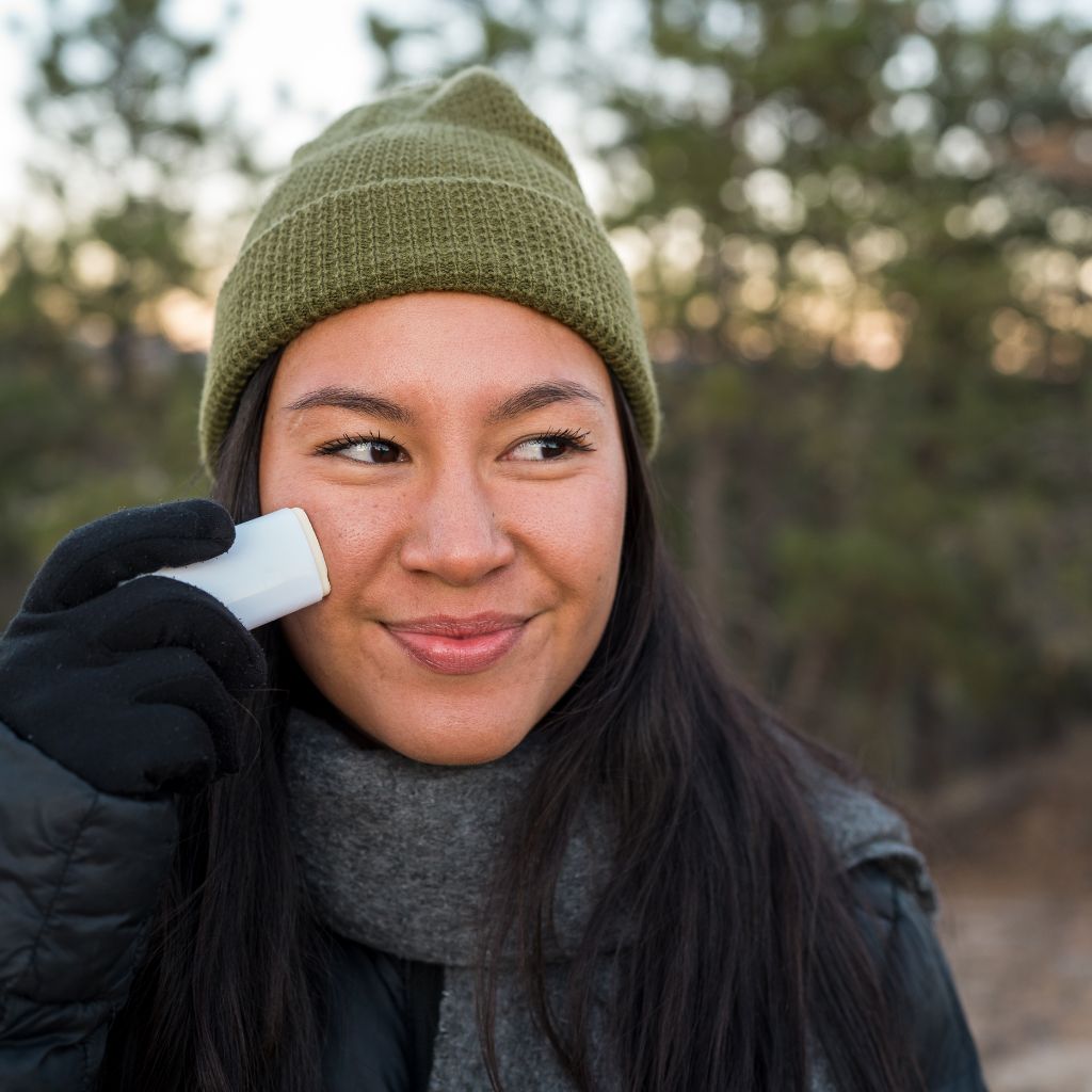 Woman in a beanie applying Face the Frost to her face