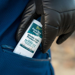 Gloved hands putting Face the Frost into a coat pocket