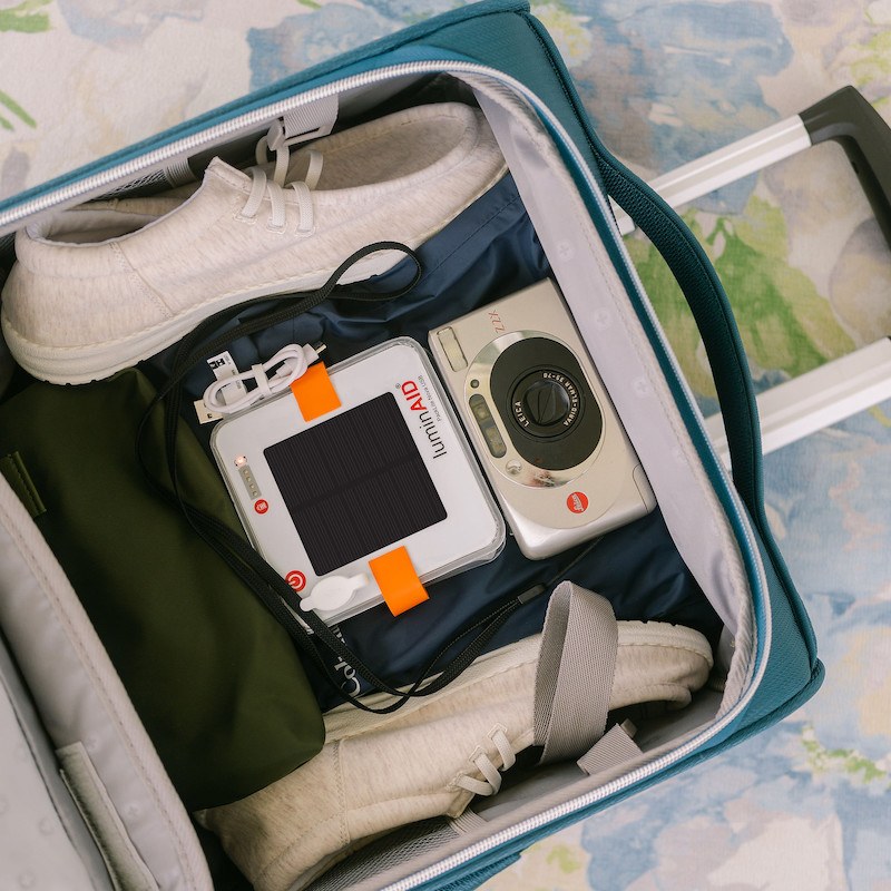 LuminAID in a suitcase with shoes and a camera