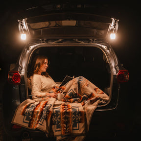 Woman reading in a van lit by Trio lanterns