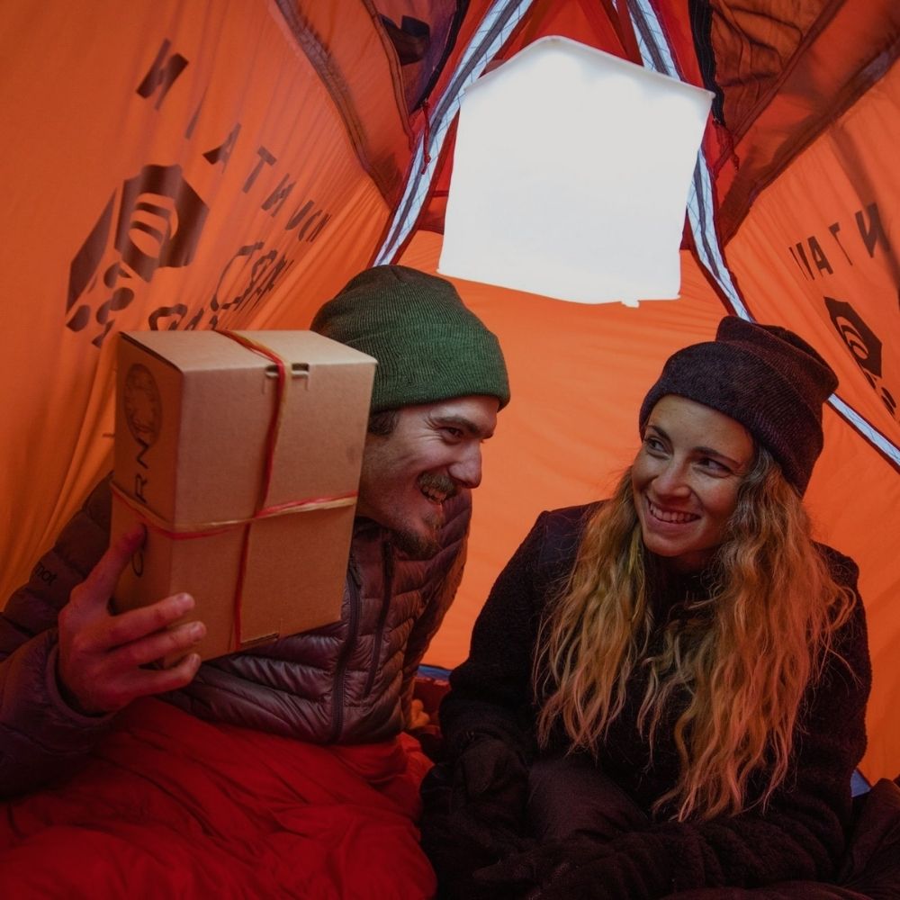Man and woman with a gift and lantern in tent.