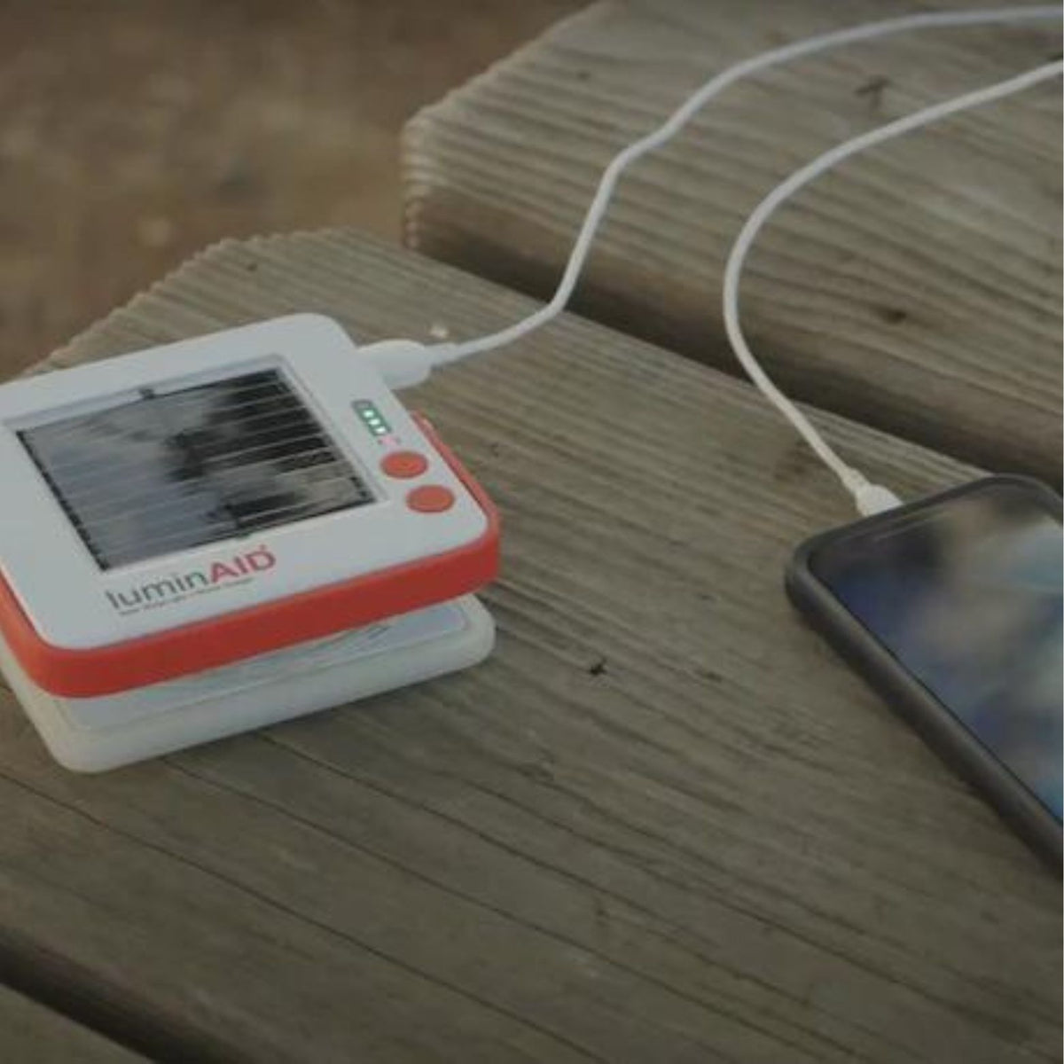 LuminAID Solar String Lights charging phone on table