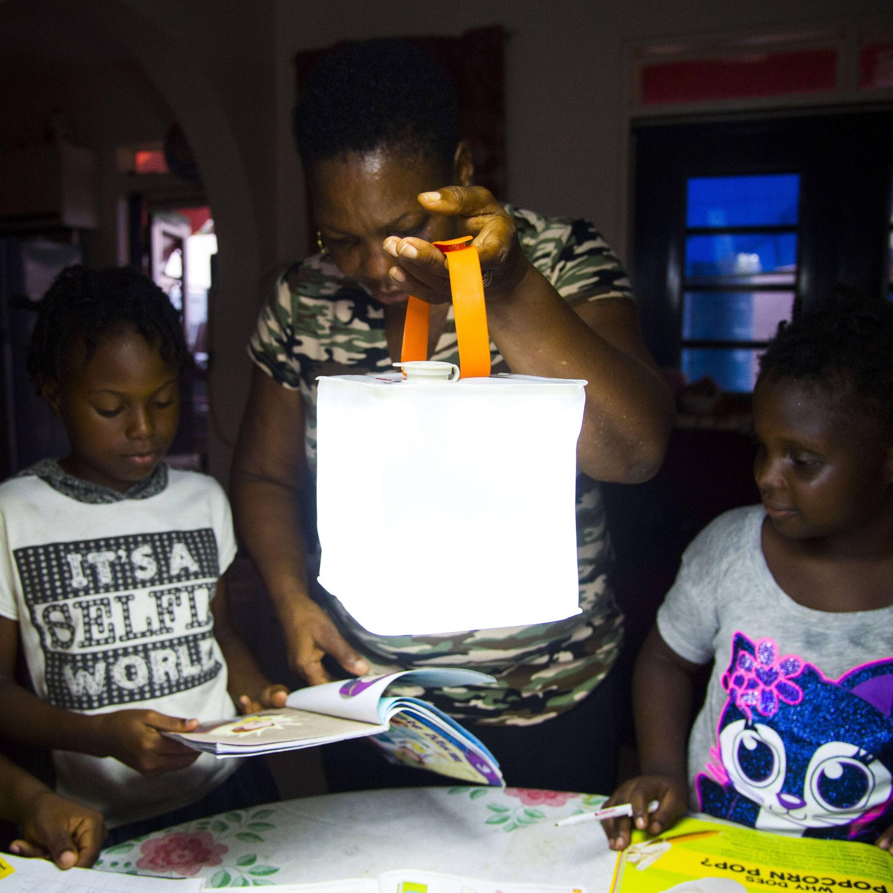 Children reading books as woman holds up lantern.