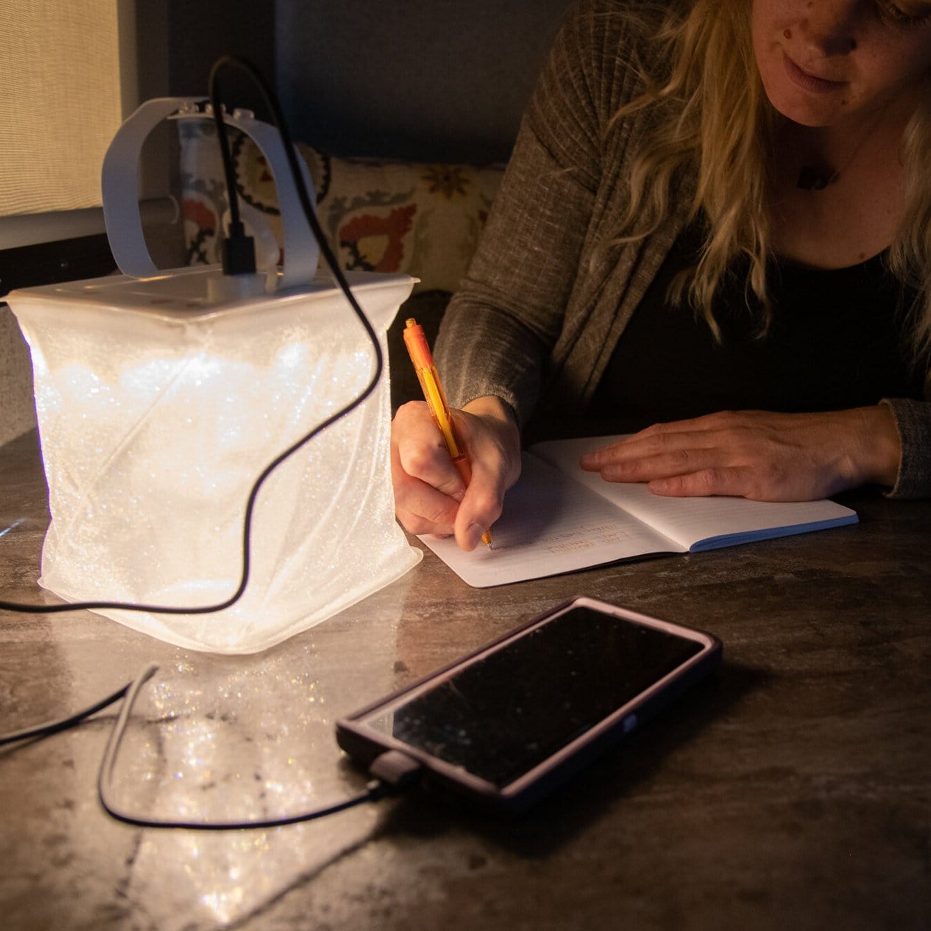 Firefly lantern lights up journal for writing and charges phone at the same time.