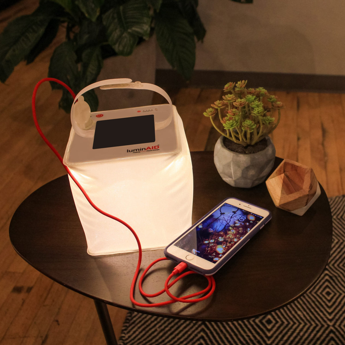 Firefly power lantern lighting up a table and charging a phone.
